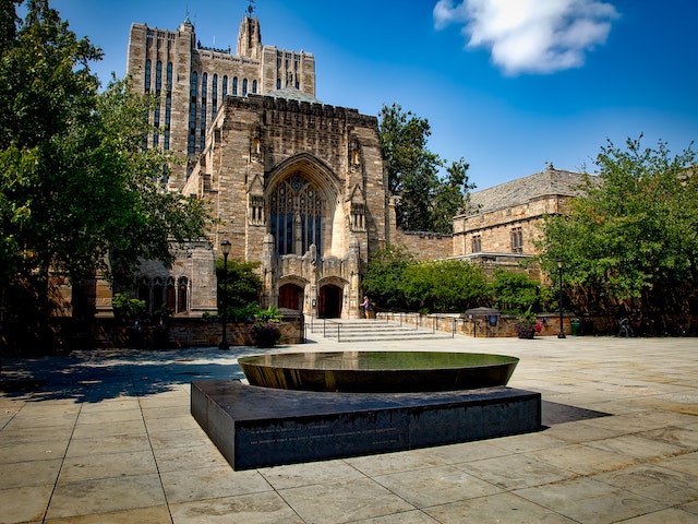 Iconic Gothic-style architecture of Yale University with lush greenery on a sunny day